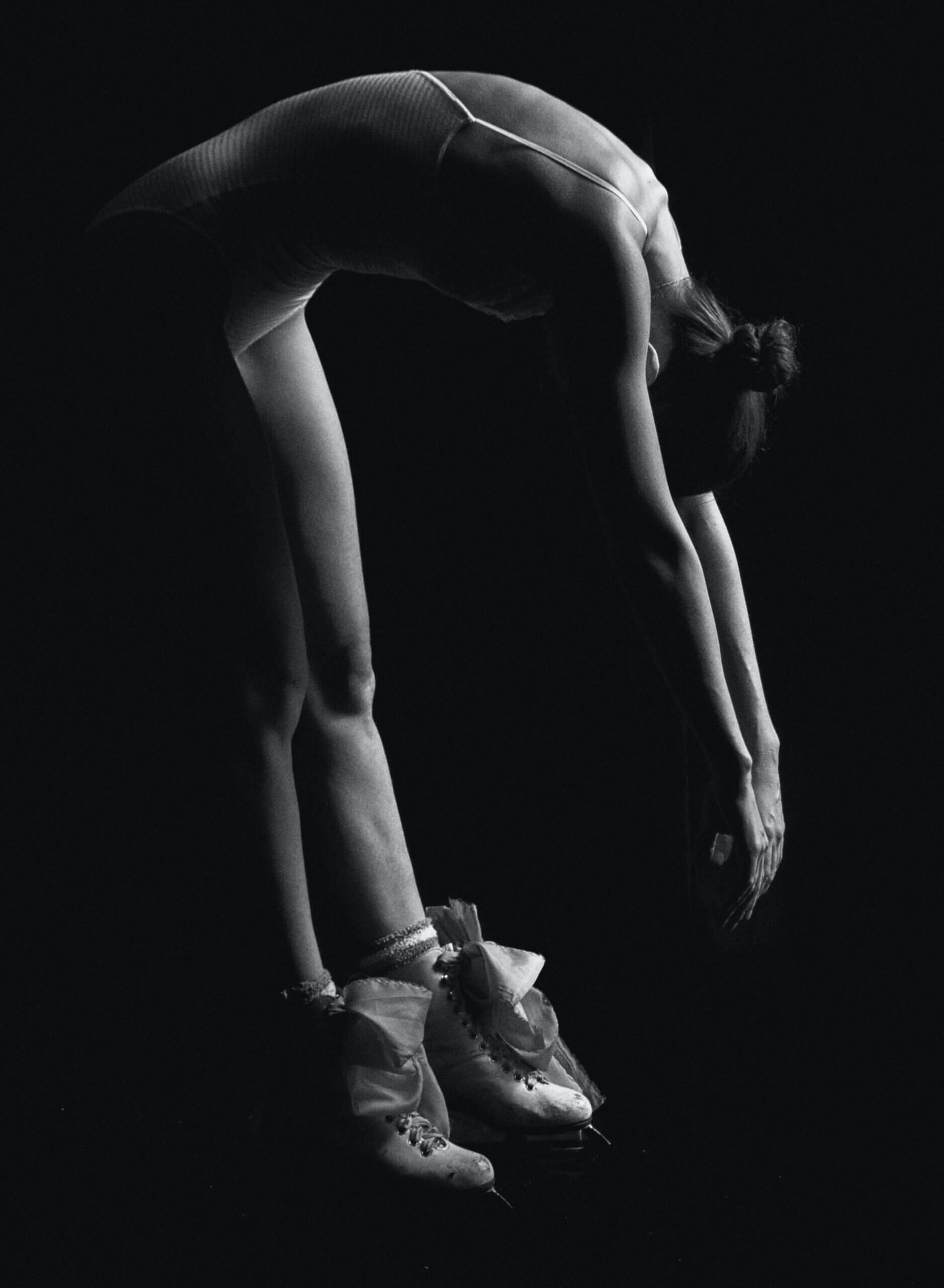 Une danseuse qui s'étire en penchant le dos en avant.